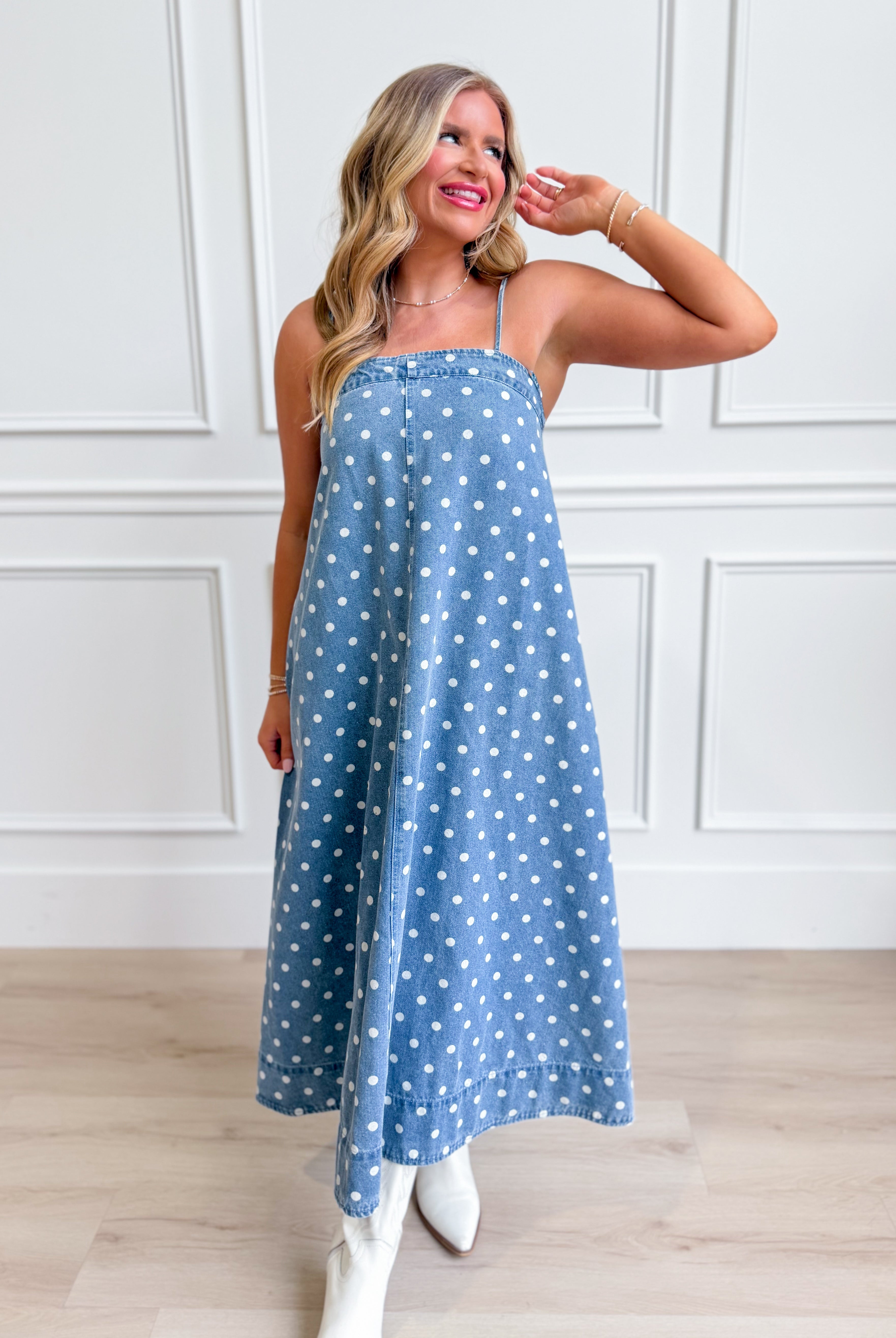 Aureum Mia Polka Dot Denim Dress displayed on a hanger, featuring a classic denim fabric with playful white polka dots.