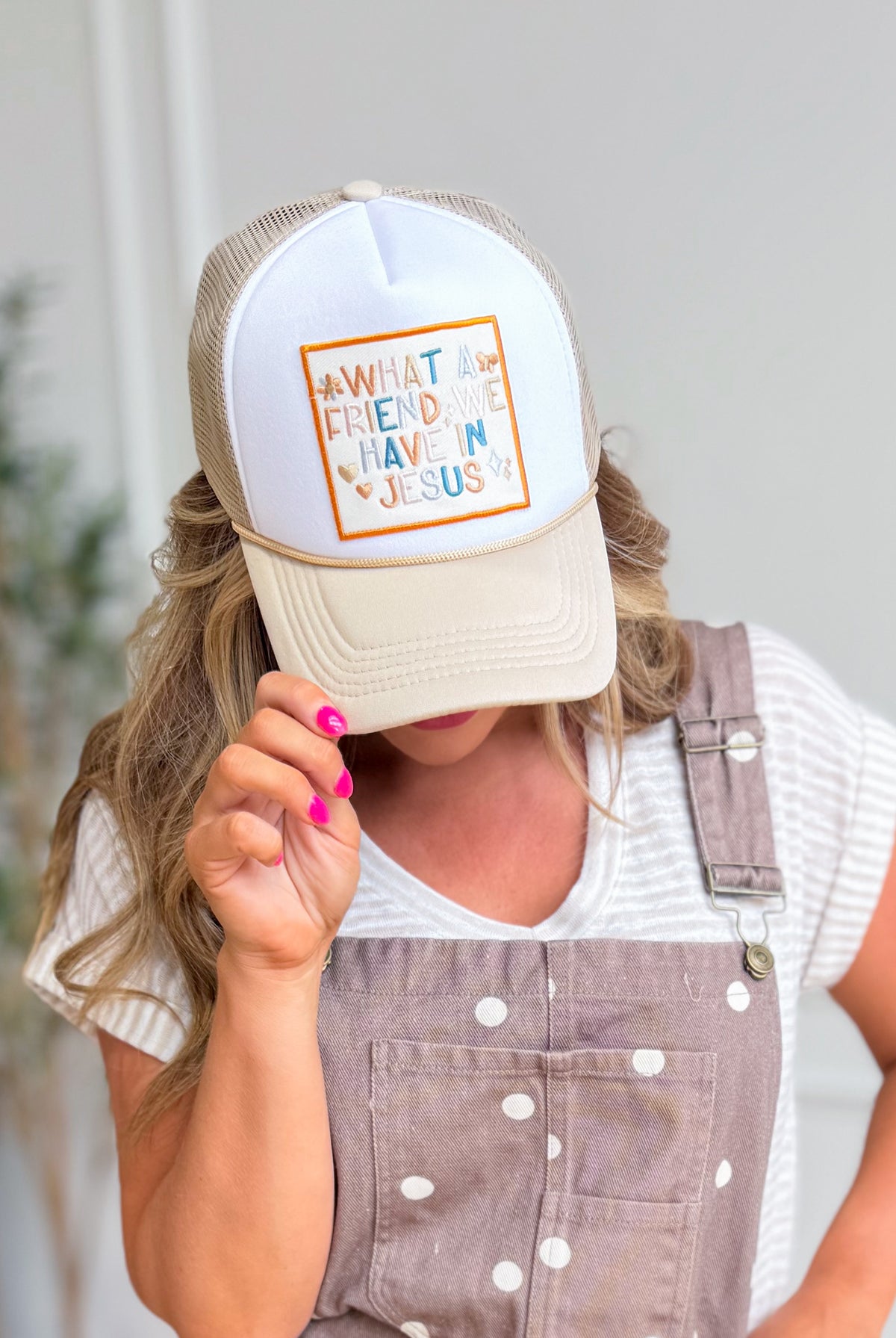 Gospel Gear Co embroidered foam trucker hat with "What A Friend In Jesus" slogan, featuring adjustable fit and mesh back.