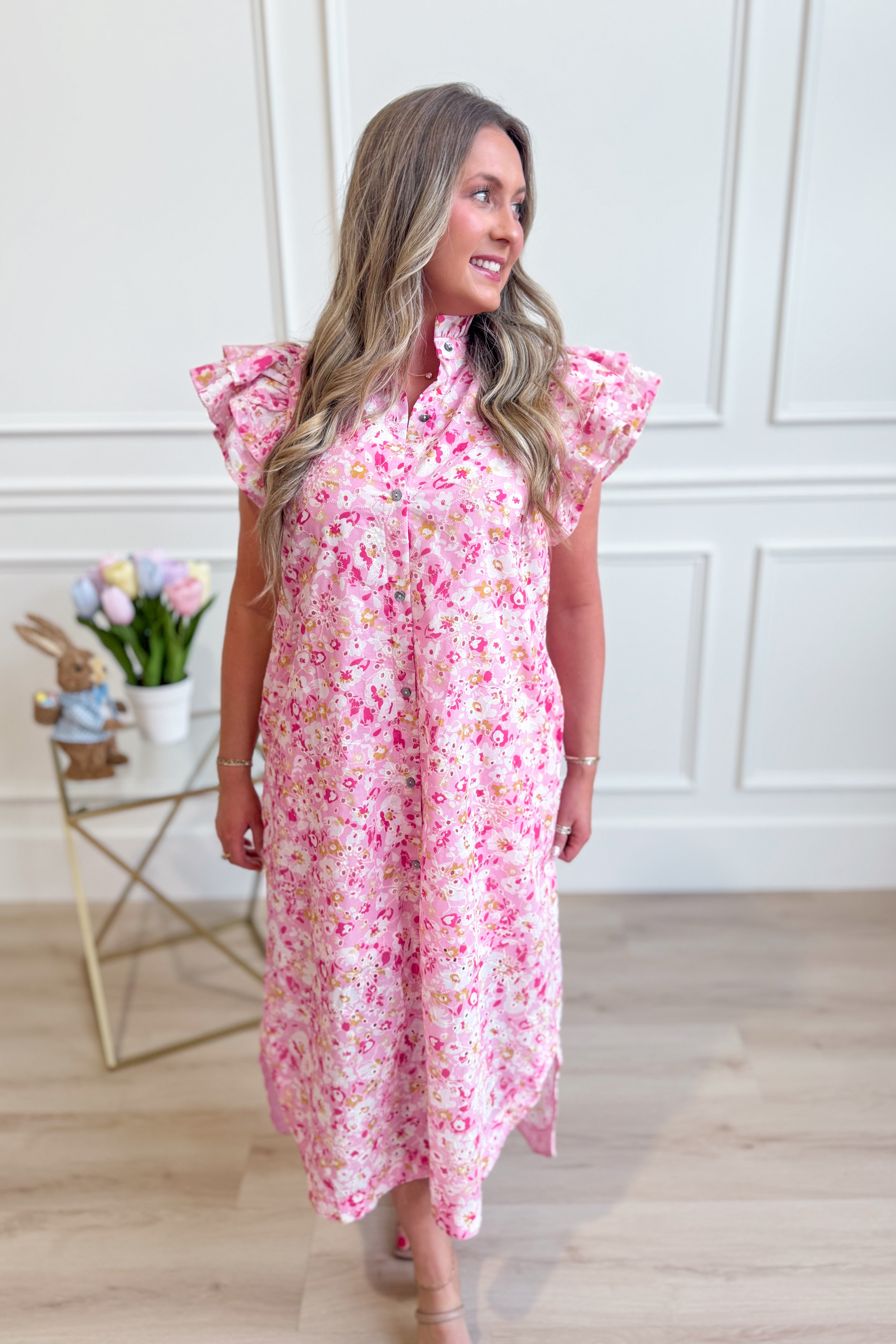 A woman wearing the ENTRO Aubrey Pink Floral Flutter Sleeve Dress with a flowy skirt and floral pattern, suitable for dressy occasions.