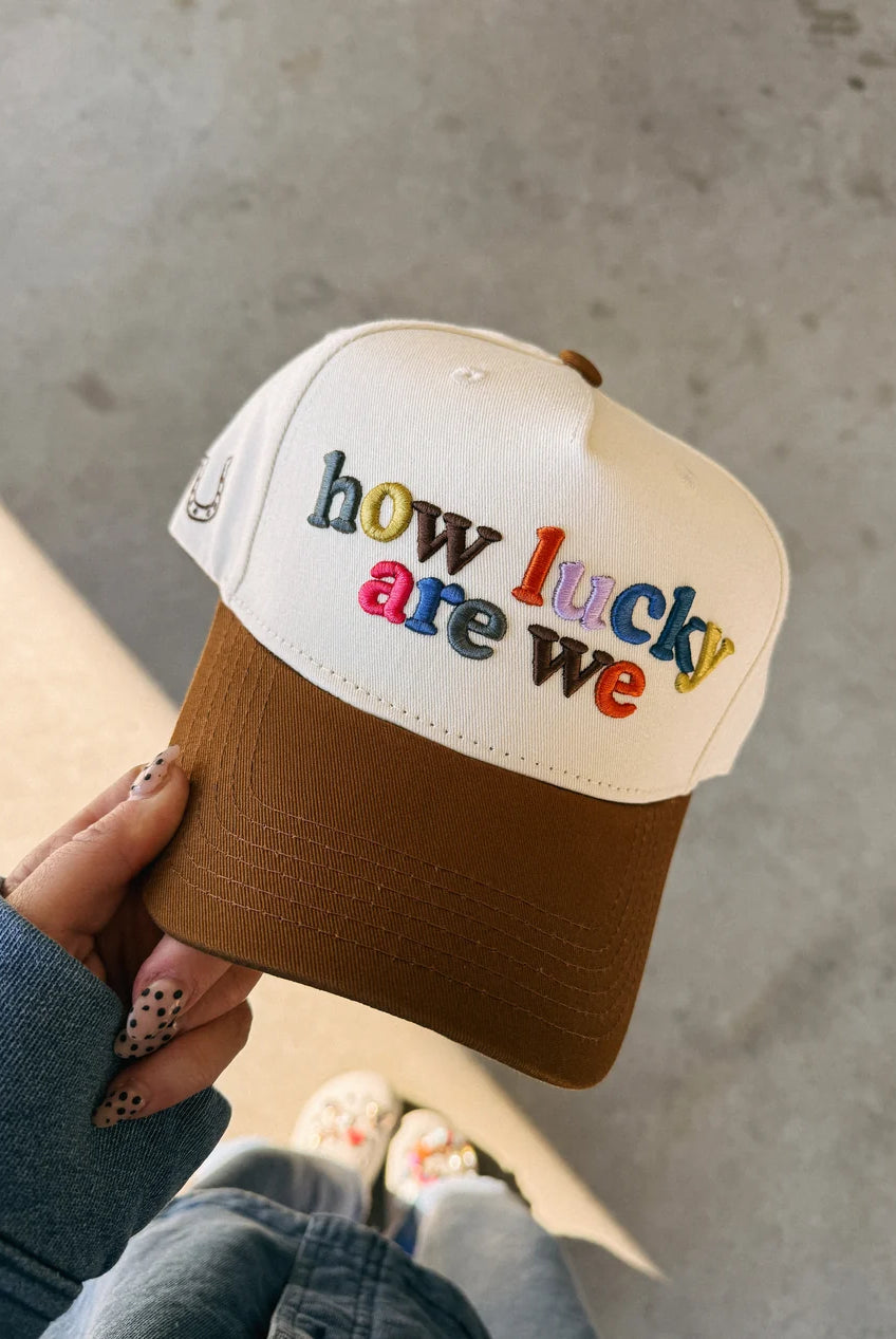 ETTA & EAST How Lucky Are We trucker hat with adjustable strap, featuring bold printed design on classic mesh cap.