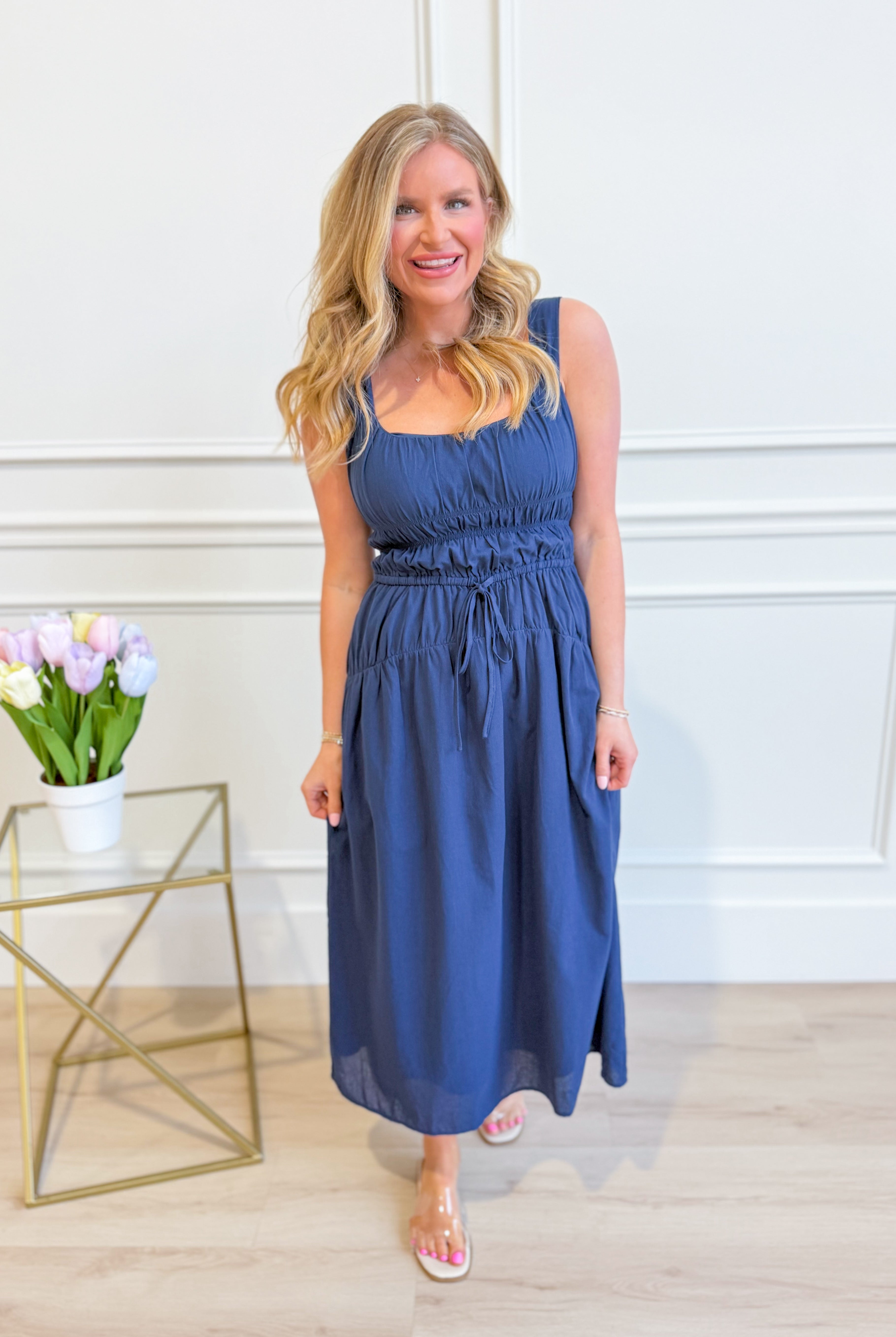 Baevly Cindy smocked tie waist midi dress styled with a flowy skirt and sleeveless design, perfect for dressy occasions.