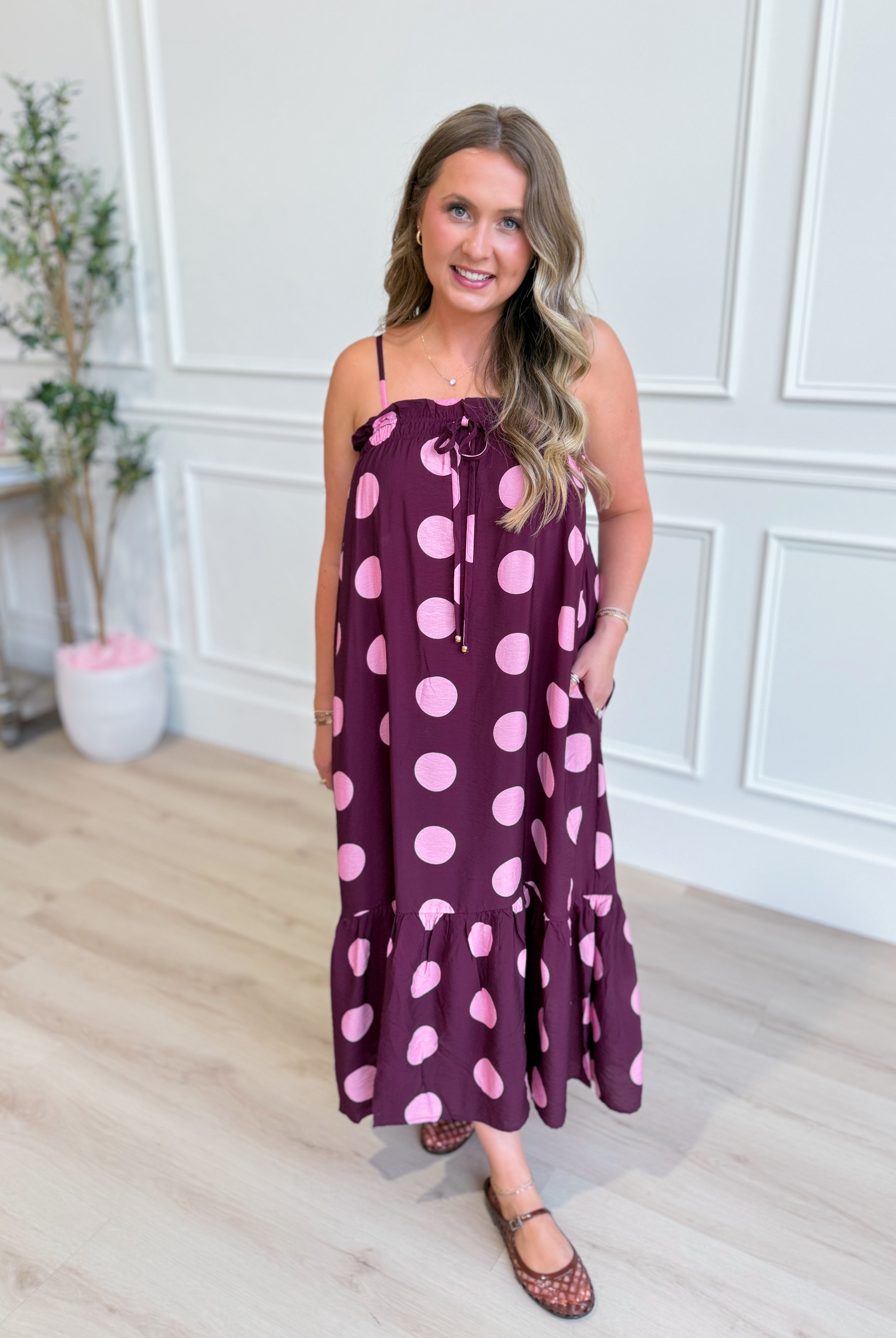 ENTRO Ashton Polka Dot Midi Dress displayed on a hanger, featuring a classic polka dot pattern and midi length for dressy occasions.