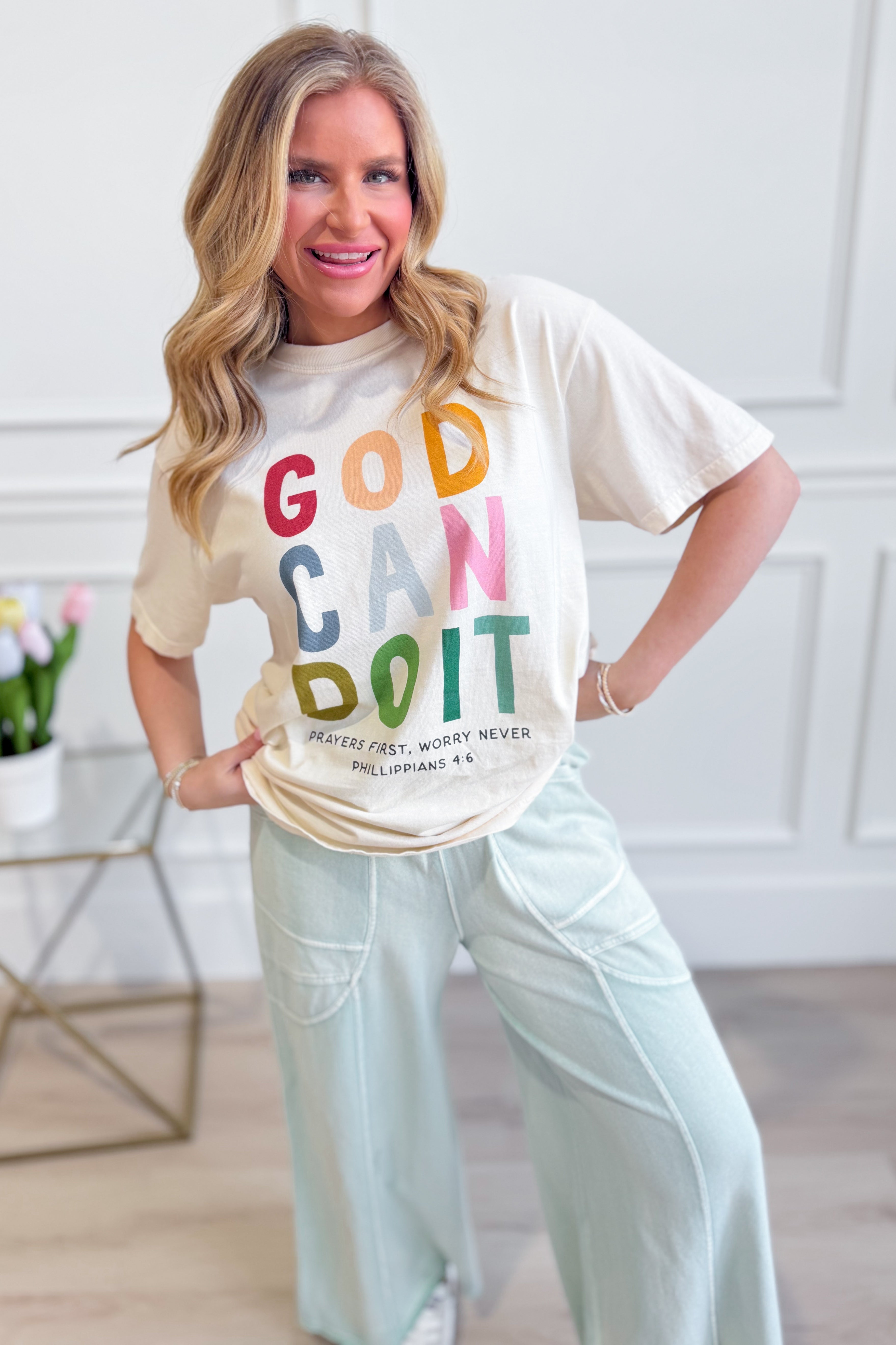 Poppy & Pine God Can Do It graphic T-shirt featuring bold text and a casual fit, displayed on a model against a white background.
