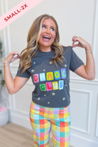 A woman modeling a dark gray graphic t-shirt with 'CHAOS CLUB' printed in colorful letters, paired with pastel plaid pants. A pink diagonal banner in the top left corner reads 'SMALL-2X'.