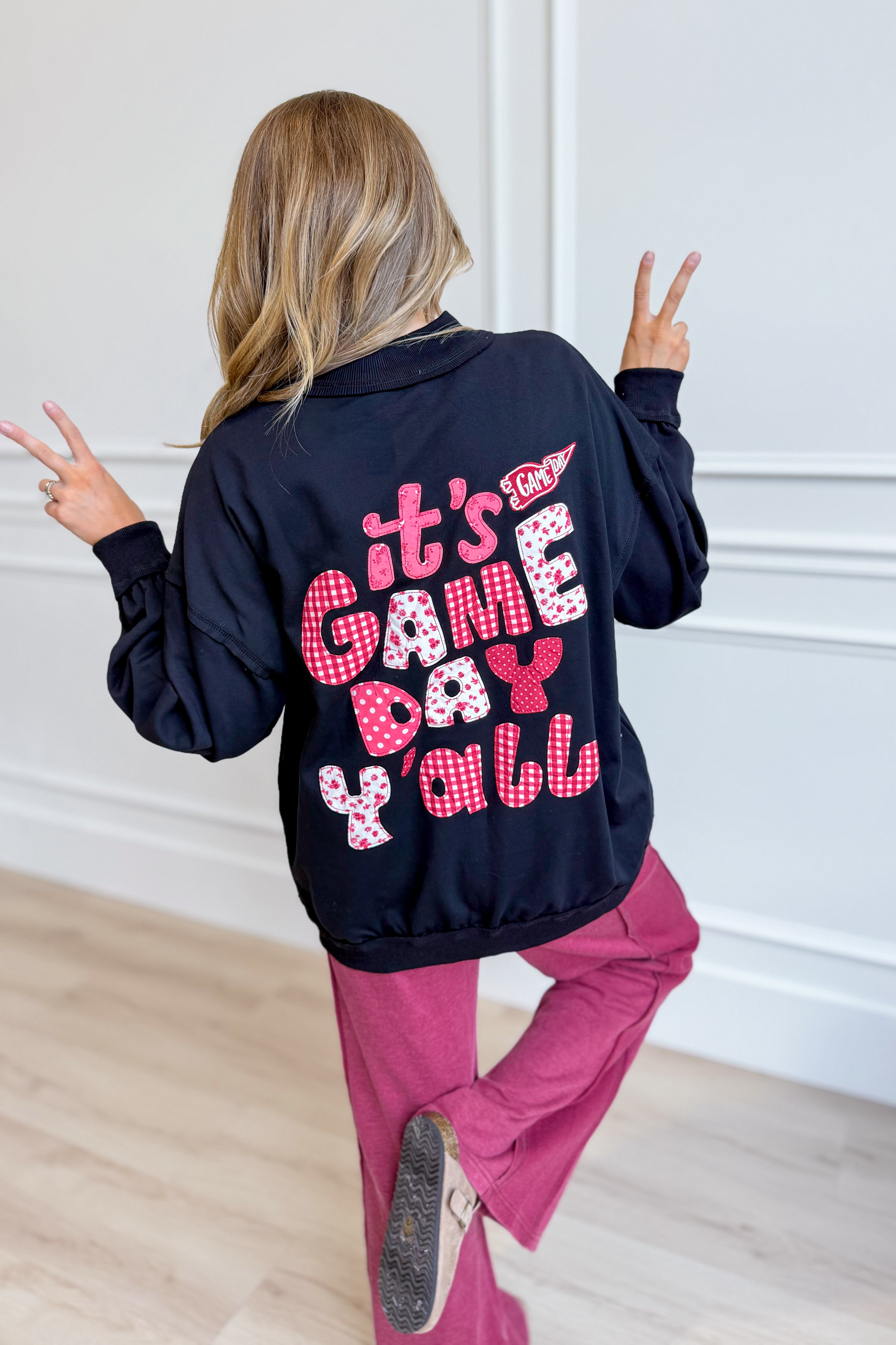 Black Cynthia Game Day Pullover from PEACH LOVE, featuring a graphic design on a cozy sweatshirt for game day comfort.