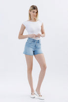 Vervet Rebecca high rise short in 146 core jeans, denim fabric with frayed hem and distressed details, worn with casual top.