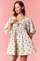 Loran cream pleated polka dot romper by PEACH LOVE with short sleeves and a relaxed fit, displayed on a hanger.