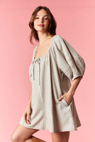 Peach Love Noah pin stripe oversized romper with relaxed fit, featuring a V-neck, short sleeves, and a tie waist detail.