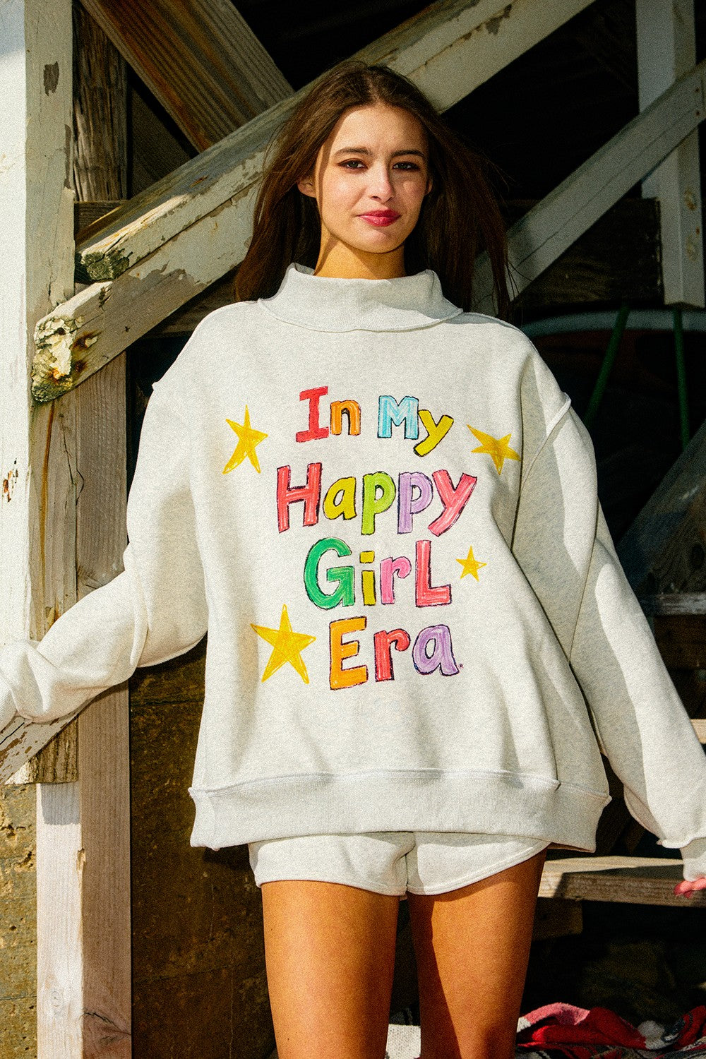 Pink "In My Happy Girl Era" BUCKET LIST graphic sweatshirt with long sleeves and casual fit, displayed on a hanger.