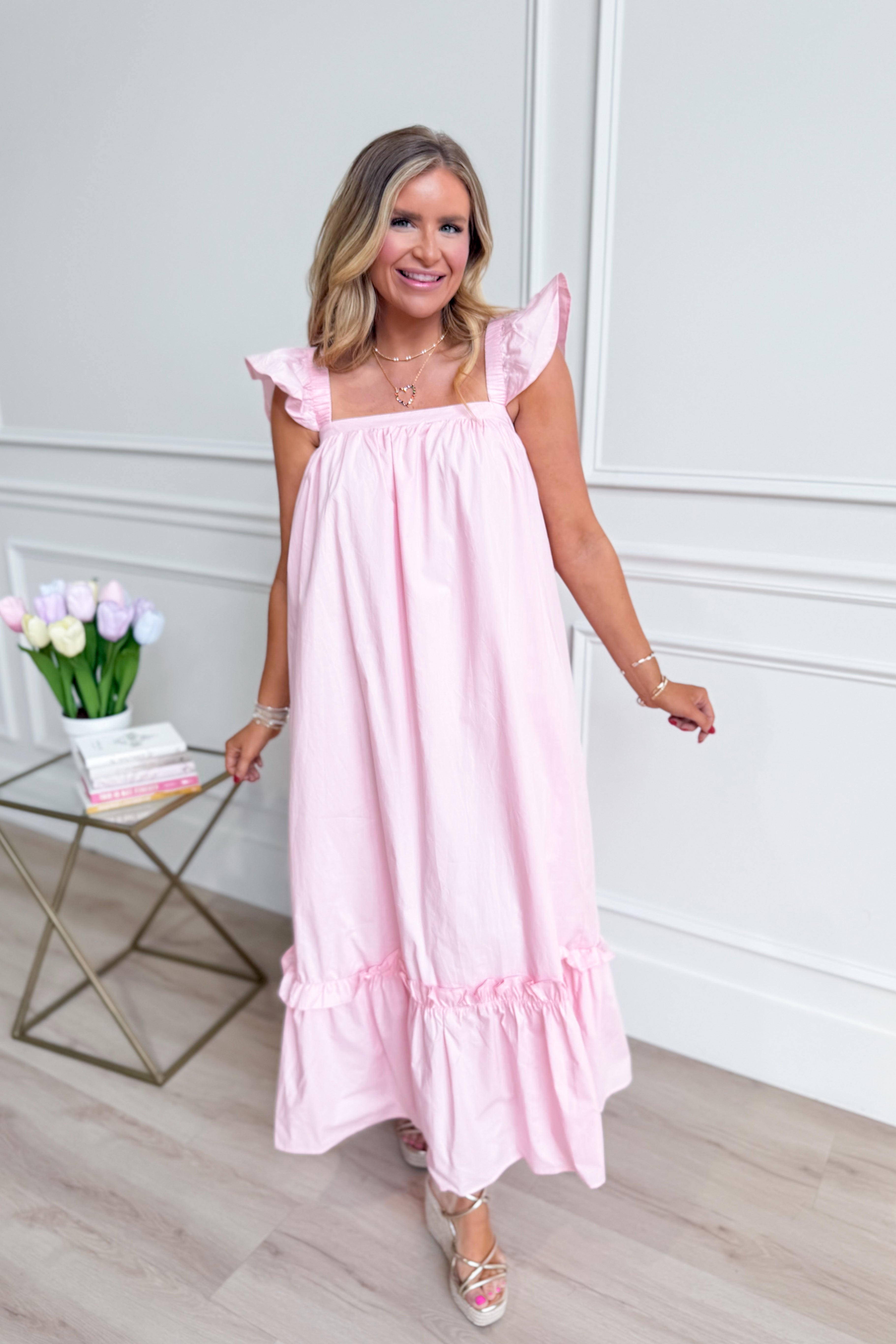 Baby pink Folly midi dress with flutter sleeves by TCEC, casual style, shown on a model standing outdoors.