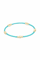 Enewton turquoise hope and purpose gold bracelet with a delicate chain and turquoise bead accents on a jewelry display.