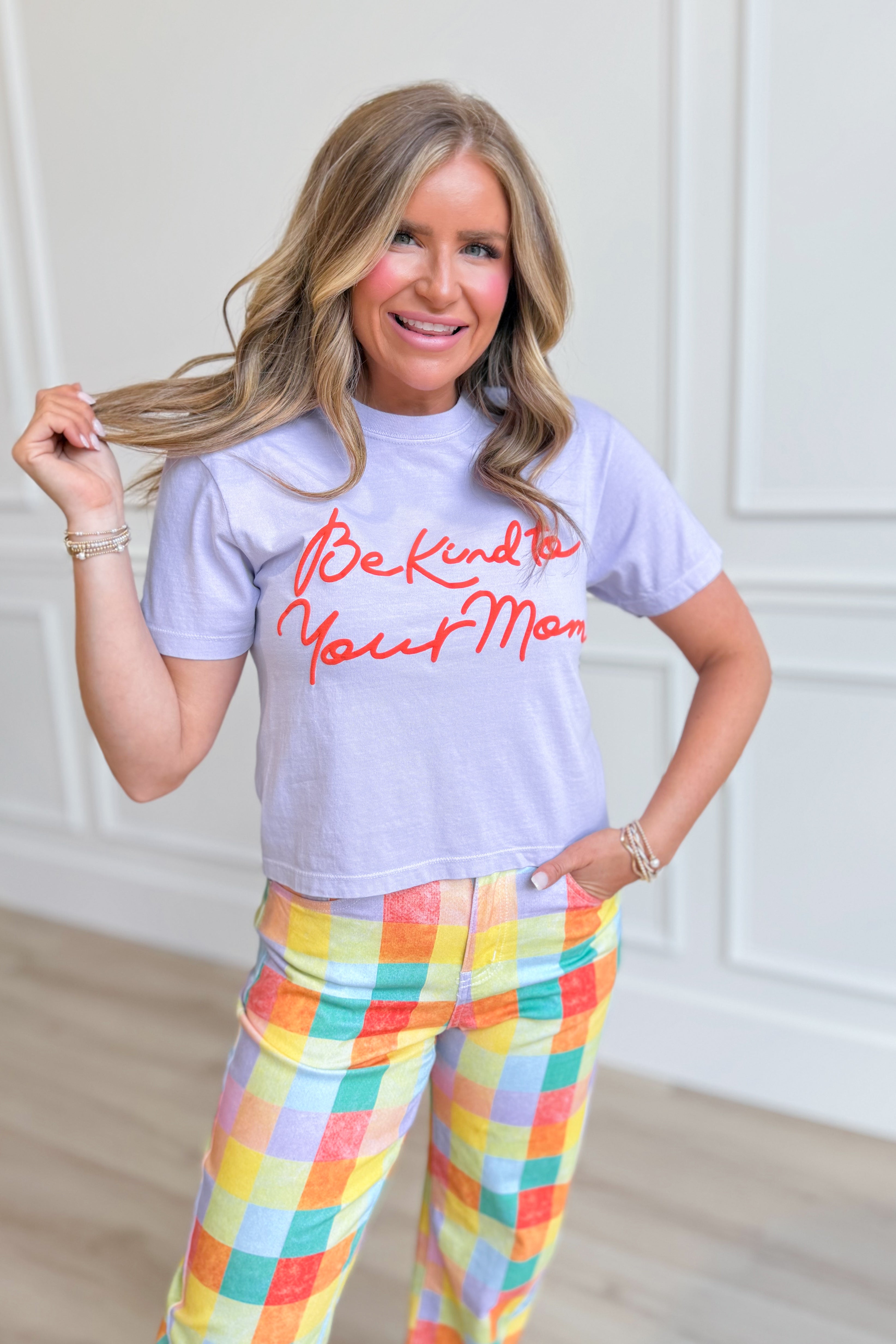 Pink crop tee from POPPY & PINE with "Be Kind To Your Mom" graphic, casual style, displayed on a hanger.