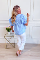 Light blue Holly puff sleeve frilly top by ENTRO, showcasing ruffled sleeves and delicate fabric details.